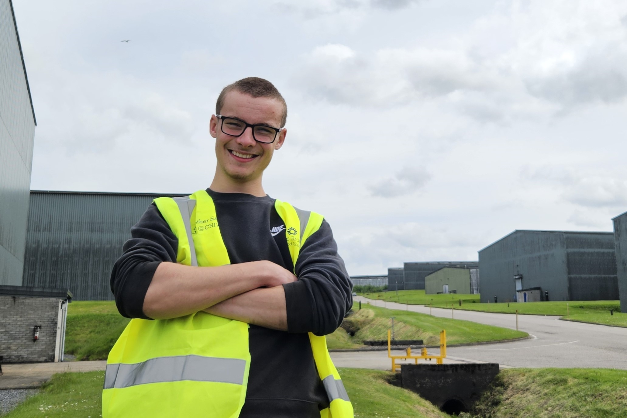 A photograph of employability client, Harry, standing outside with distillery bond buildings behind him